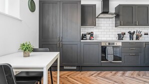 A modern kitchen with dark cabinets, a white countertop, and a built-in oven. - Boho Vista| Stylish Central1BR Flat in Cardiff Bay (Cardiff)