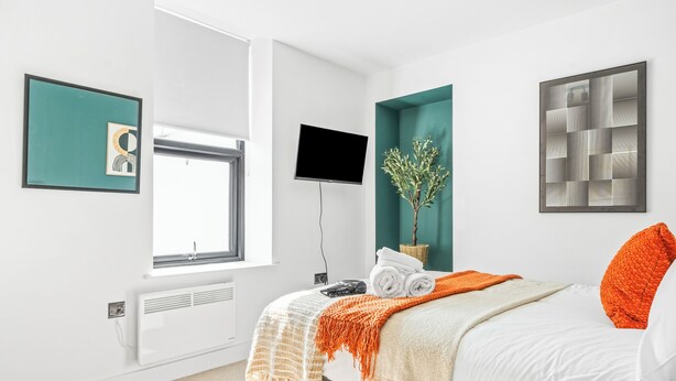 A modern bedroom with a bed, a TV, and artwork on the walls. - Boho Vista| Stylish Central1BR Flat in Cardiff Bay (Cardiff)