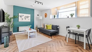 A modern living room with a sofa, a dining table, and a TV. - Boho Vista| Stylish Central1BR Flat in Cardiff Bay (Cardiff)