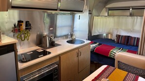 A compact kitchen with a sink, stove, and storage cabinets.