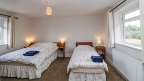 Une chambre avec deux lits, chacun étant équipé d’une lampe et d’une fenêtre.