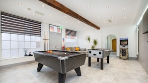Un espace de loisirs intérieur moderne comprenant une table de billard, une table de baby-foot et un jeu de baby-foot électronique.