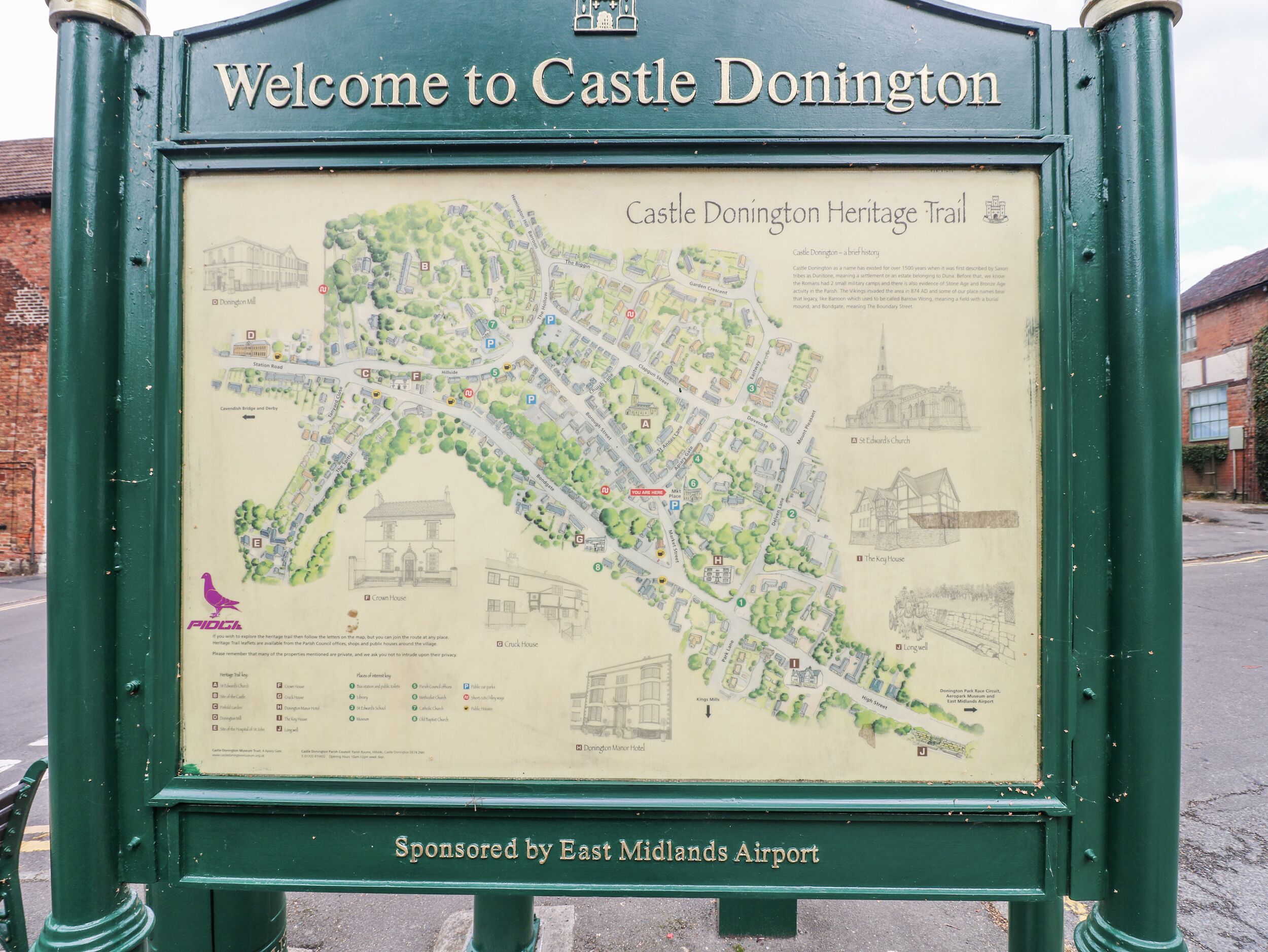 Señal de bienvenida para la ruta del patrimonio de Castle Donington, patrocinada por el Aeropuerto de East Midlands, que muestra un mapa de la ruta con puntos de referencia como Crown House y la iglesia de St Edwards.