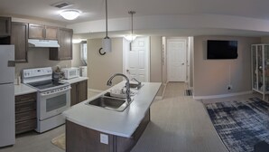 A modern kitchen with a central island, built-in appliances, and a large window. - Spacious one bedroom Basement Apartment (Belleville)
