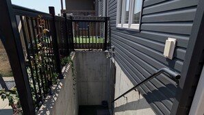 A house entrance with a concrete staircase, a black metal gate, and a red doormat with the word "hello". - Spacious one bedroom Basement Apartment (Belleville)