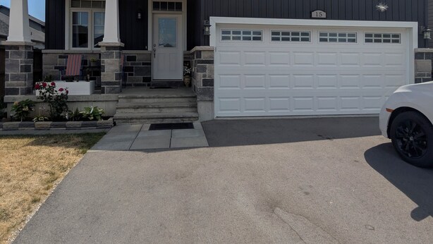 A two-story house with a garage, a front porch, and a driveway. - Spacious one bedroom Basement Apartment (Belleville)