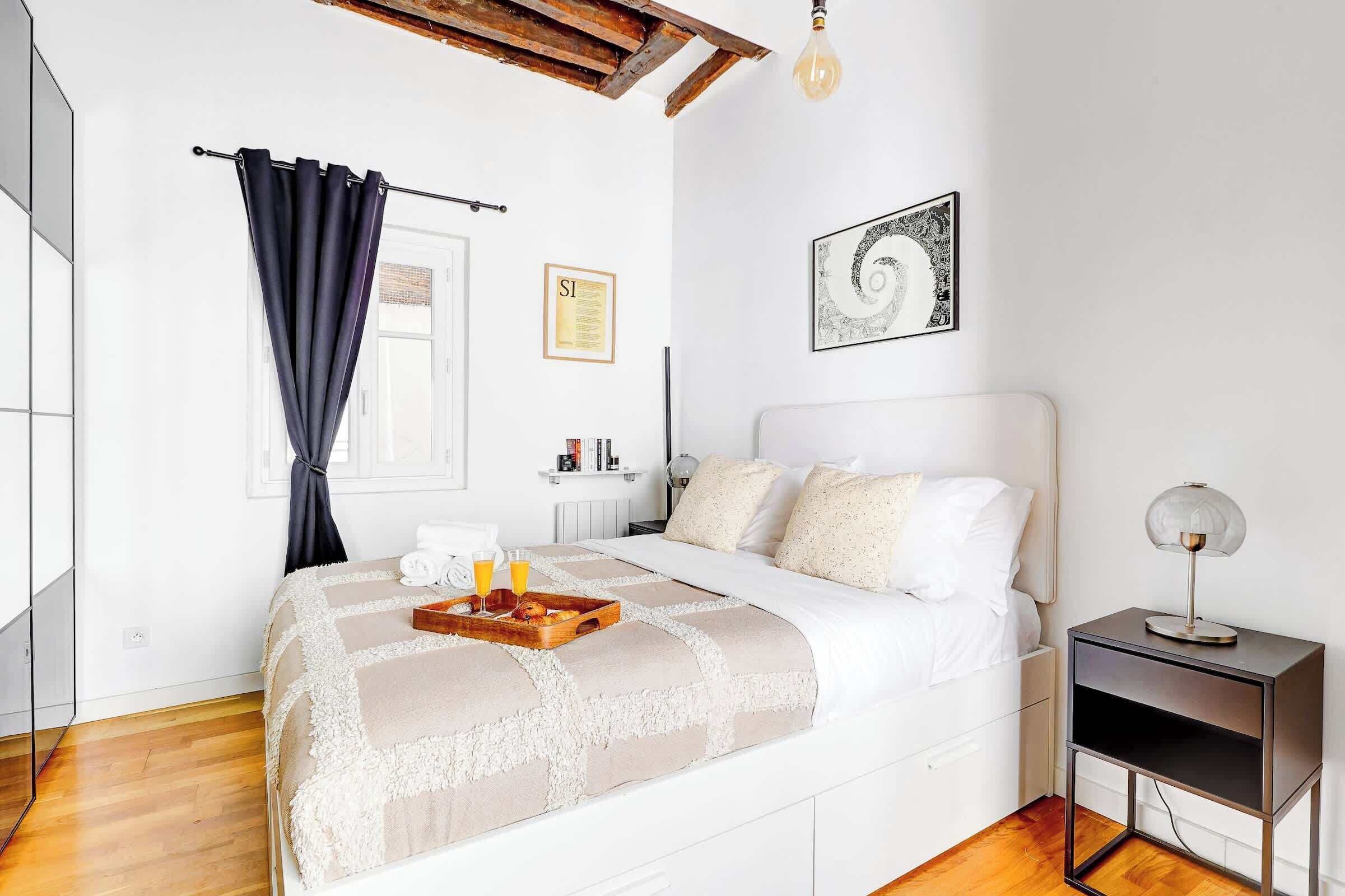 Een moderne slaapkamer met een bed, nachtkastje en een klein tafeltje.