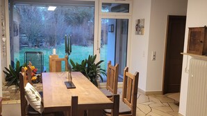 A dining area with a wooden table and chairs, a candle centerpiece, and a view of a garden through glass doors. - Vacation home Schmidt with Nicole and Frank (Oberzent)