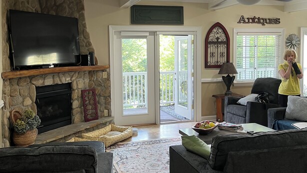 A living room with a stone fireplace, a flat-screen TV, and a ceiling fan. - Beautiful townhome in the village of Banner elk It doesn’t get better than this. (Banner Elk)