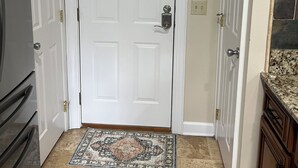 A hallway with a white door, a "gather" sign above it, a patterned rug, and a clock on the wall. - Beautiful townhome in the village of Banner elk It doesn’t get better than this. (Banner Elk)