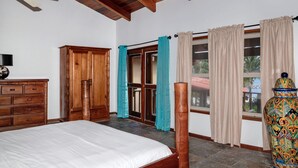 A bedroom with a bed, wooden wardrobe, and a large vase.