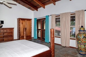 A bedroom with a bed, wooden wardrobe, and a large vase.