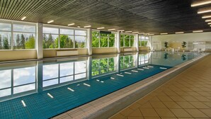 An indoor swimming pool with clear windows, a tiled floor, and a ceiling with linear lights. - Apartment 'Superior 238' with Mountain View, Shared Garden, and Wi-Fi (Braunlage)