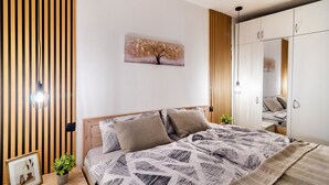 A bedroom with a bed, a bedside table with a plant, a framed picture, and a wall-mounted painting. - Apartment 'Superior 238' with Mountain View, Shared Garden, and Wi-Fi (Braunlage)