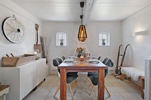 Un comedor con mesa de madera, sillas, lámpara colgante y elementos decorativos rústicos.