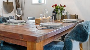 A wooden dining table set with plates, glasses, and candles, with a rustic decor including a shovel and branches. - Holiday Home 'Deichkate' – Vacation in a Historic Monument with Panoramic Views (Dagebüll)