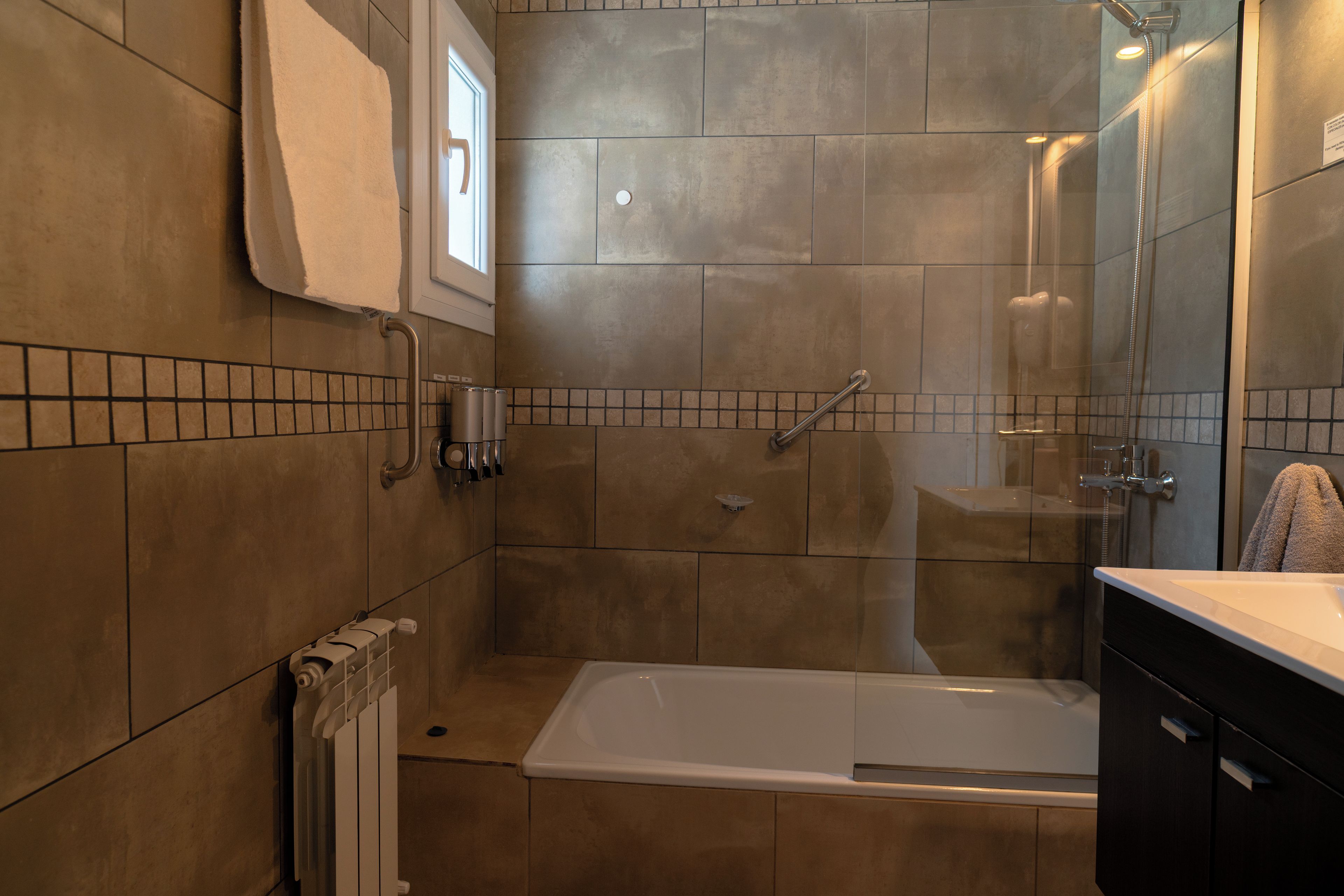 Een moderne badkamer met een bad, een douche en een toilet.