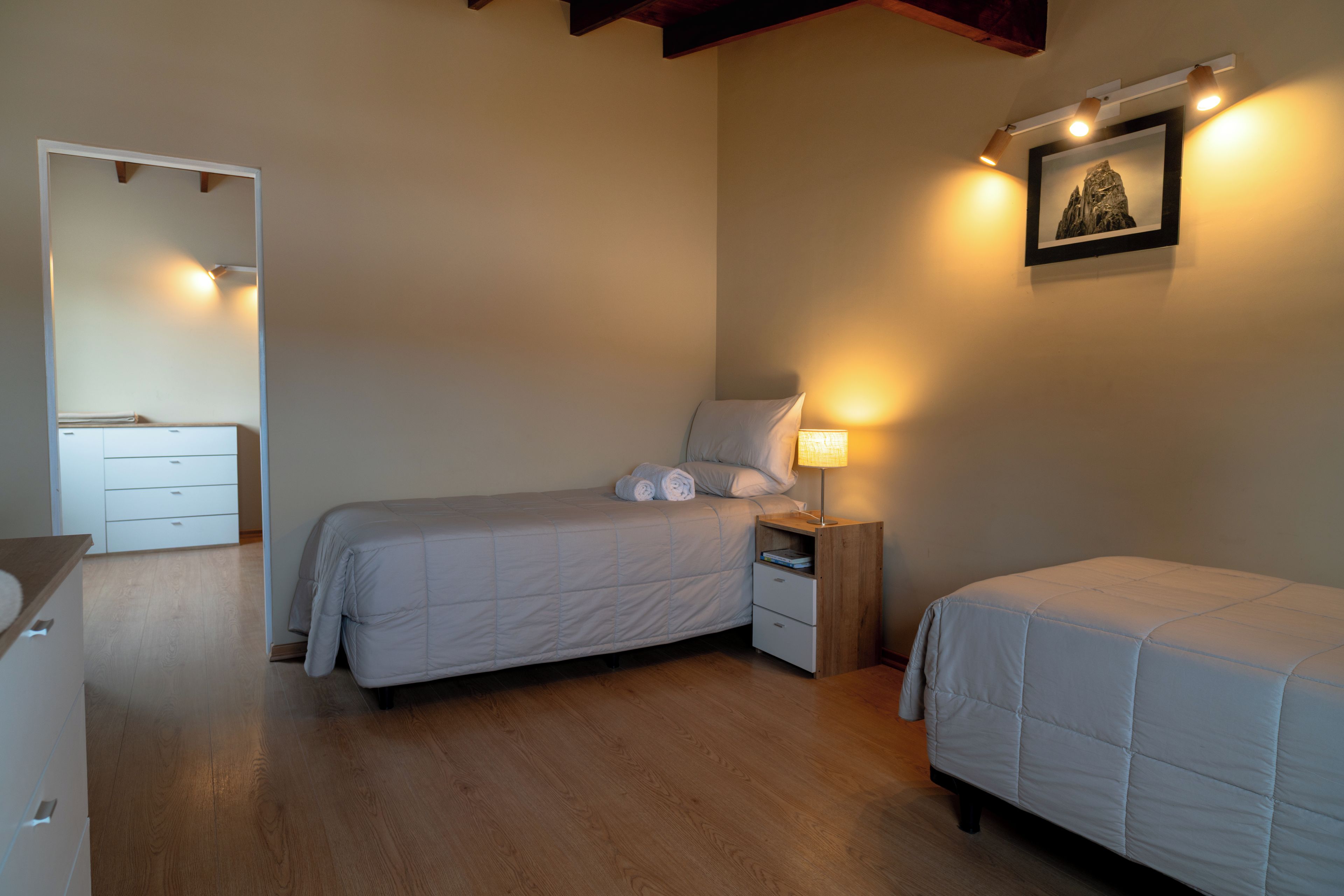 A bedroom with a bed, bedside tables, a nightstand, a dresser, and a framed picture on the wall.