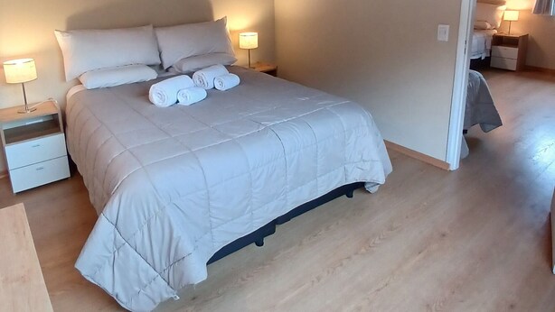 A bedroom with a bed, two bedside tables, and a wooden ceiling. - MerKaba Aparts (El Chalten)