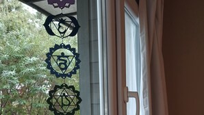A window with a curtain and a decorative hanging with symbols. - MerKaba Aparts (El Chalten)