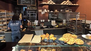 Un mostrador de panadería con diversas pastas y un panel mostrando opciones como café expreso y capuchino.