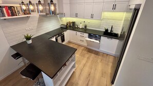 Una cocina moderna con gabinetes blancos, una encimera negra y un lavavajillas empotrado.