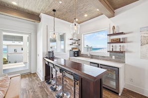 A modern kitchen with a central island, bar stools, and a view of the ocean.