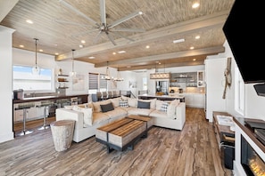 A spacious living area with a large sectional sofa, a wooden coffee table, and a ceiling fan.