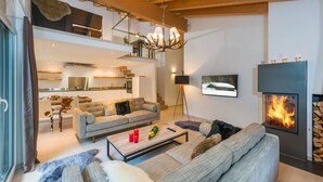Un salon moderne avec une cheminée, un canapé, une table basse et un téléviseur.
