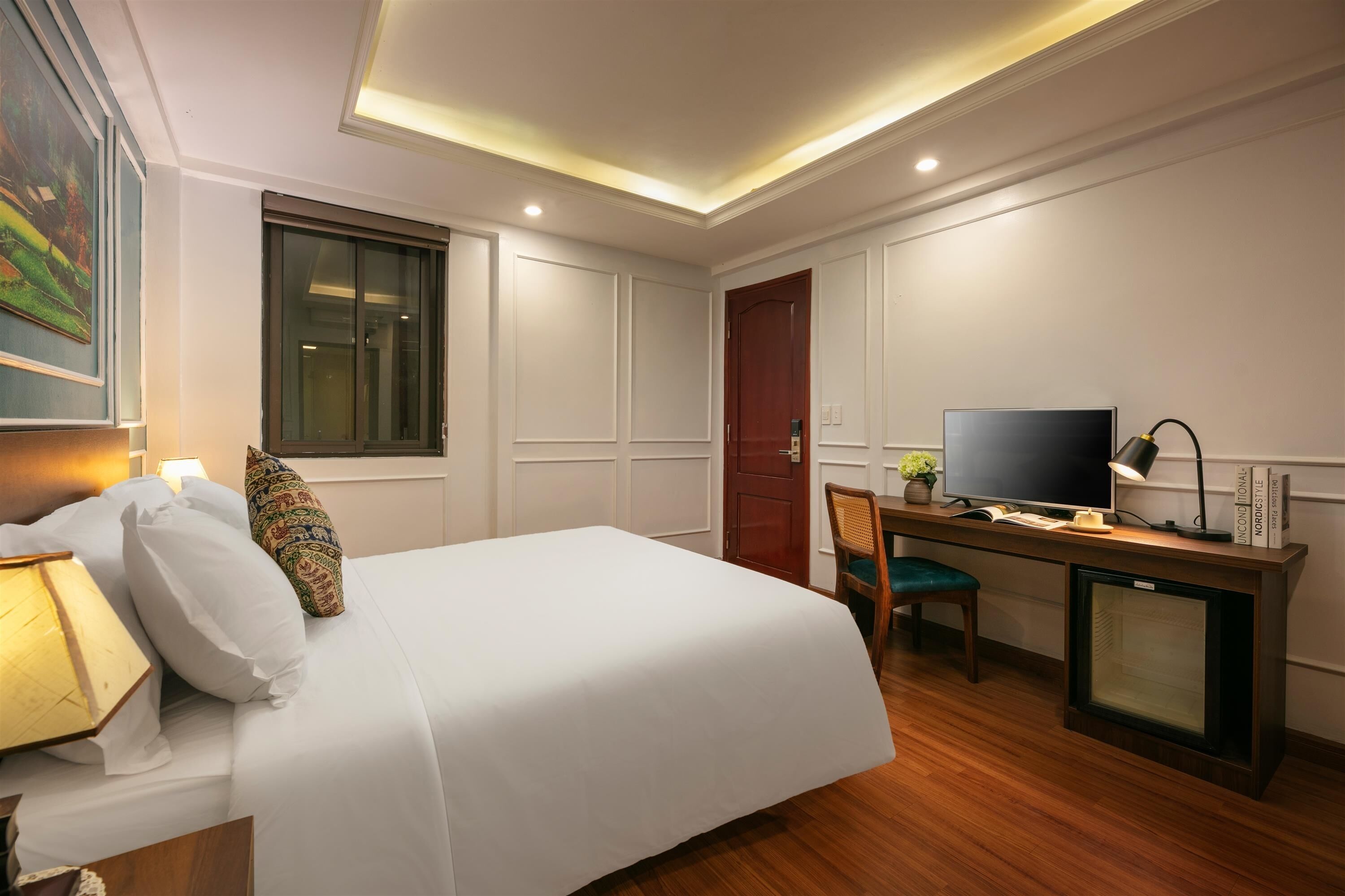 Una habitación de hotel con cama, escritorio con televisor, silla y ventana.