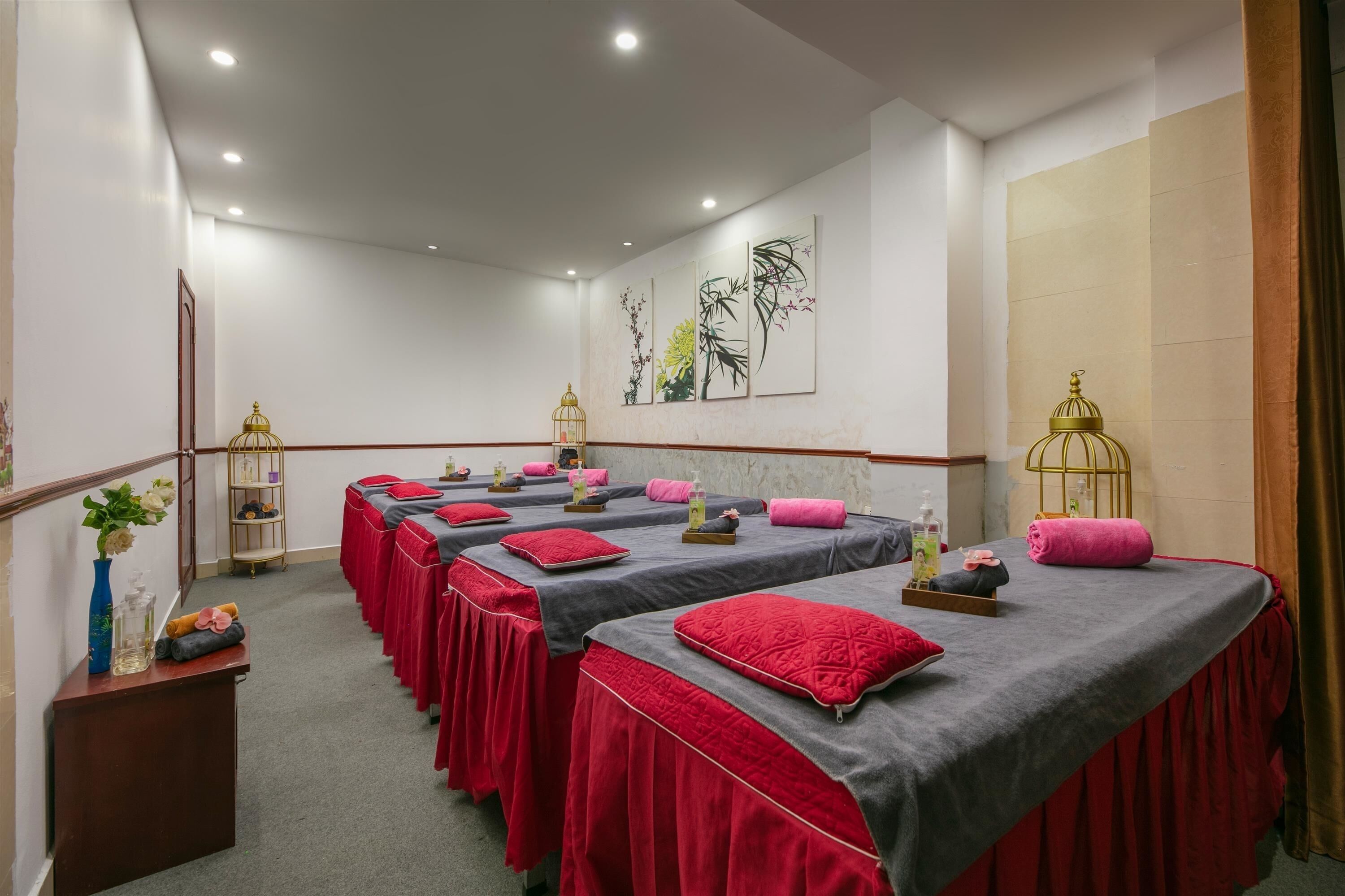 A spa room with multiple massage tables, each with a red towel and pillow.