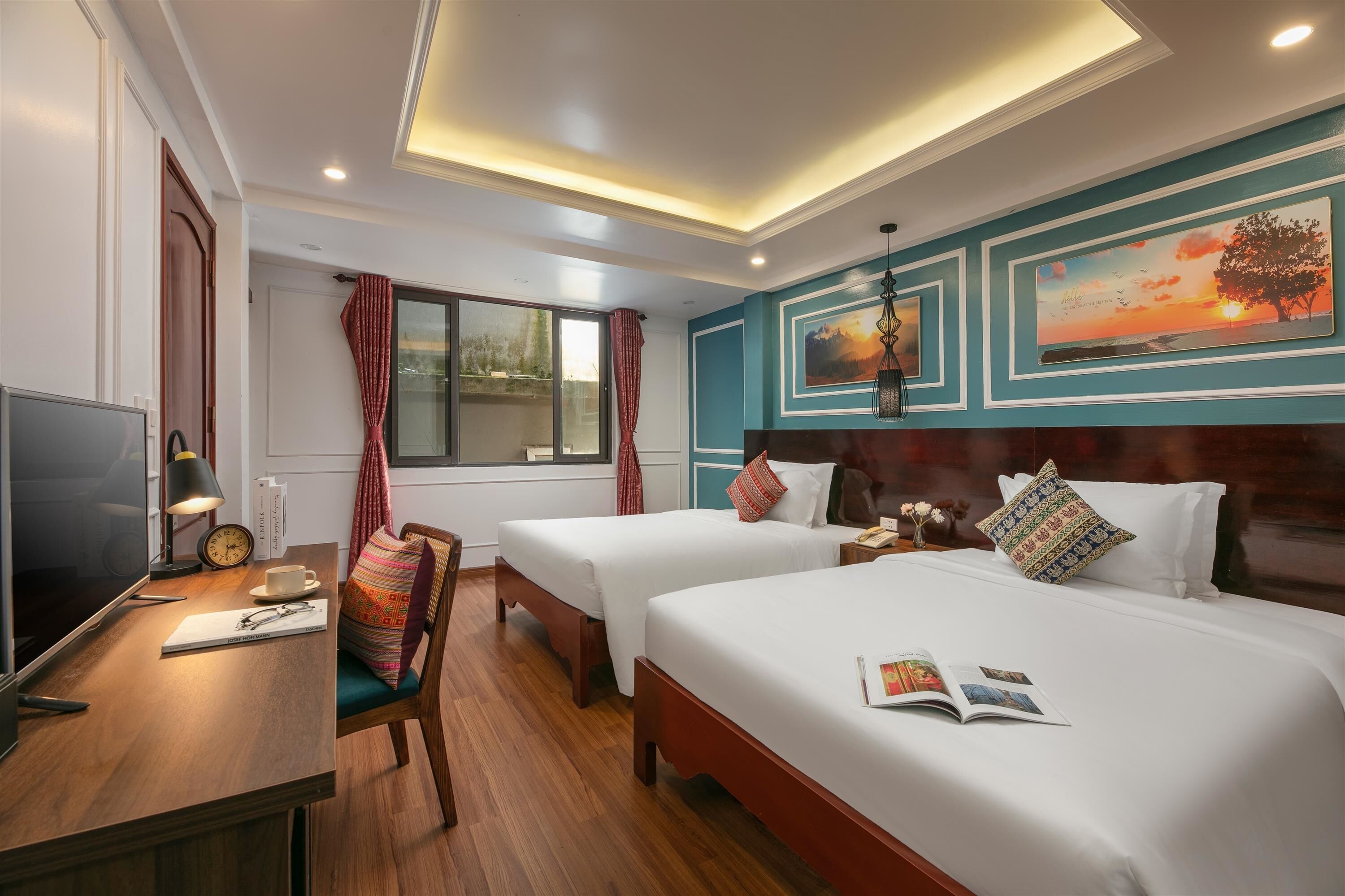 Habitación de hotel con dos camas, un escritorio con televisor y una ventana con cortinas.