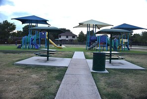 A playground with slides and climbing structures, surrounded by picnic tables and covered seating areas. - FL001 | Flower Mound Home | 3BD | Yard | Workspace (Flower Mound)