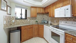 Una cocina con armarios de madera, microondas, horno y lavavajillas.