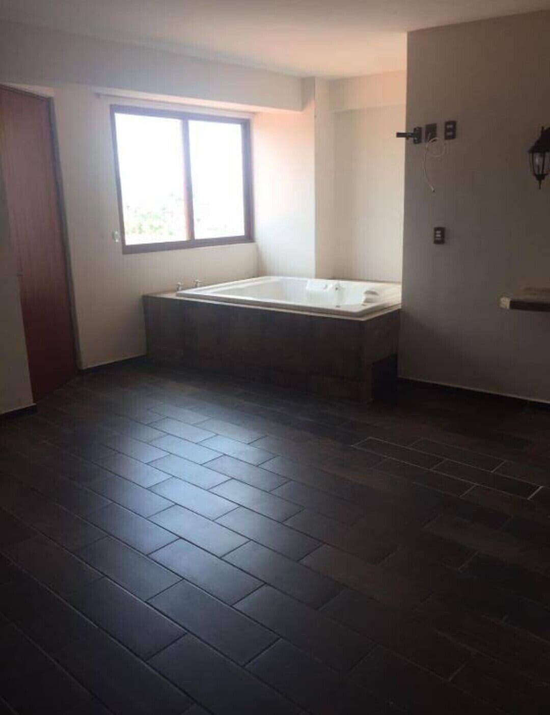 Un baño con una bañera, una ventana y una puerta.