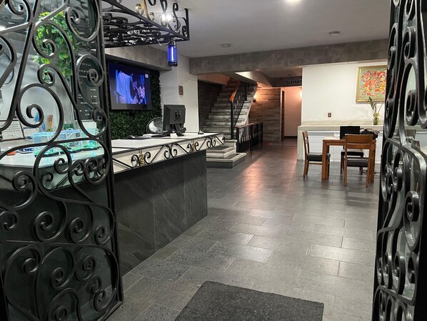 A reception area with a counter, a television, and a staircase leading to an upper floor.
