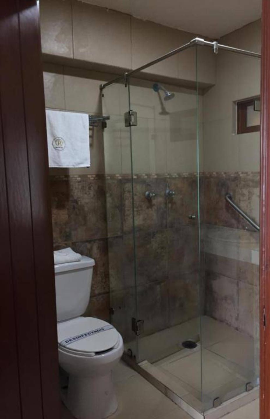 Box de chuveiro com vidro e sanita no quarto adjacente.