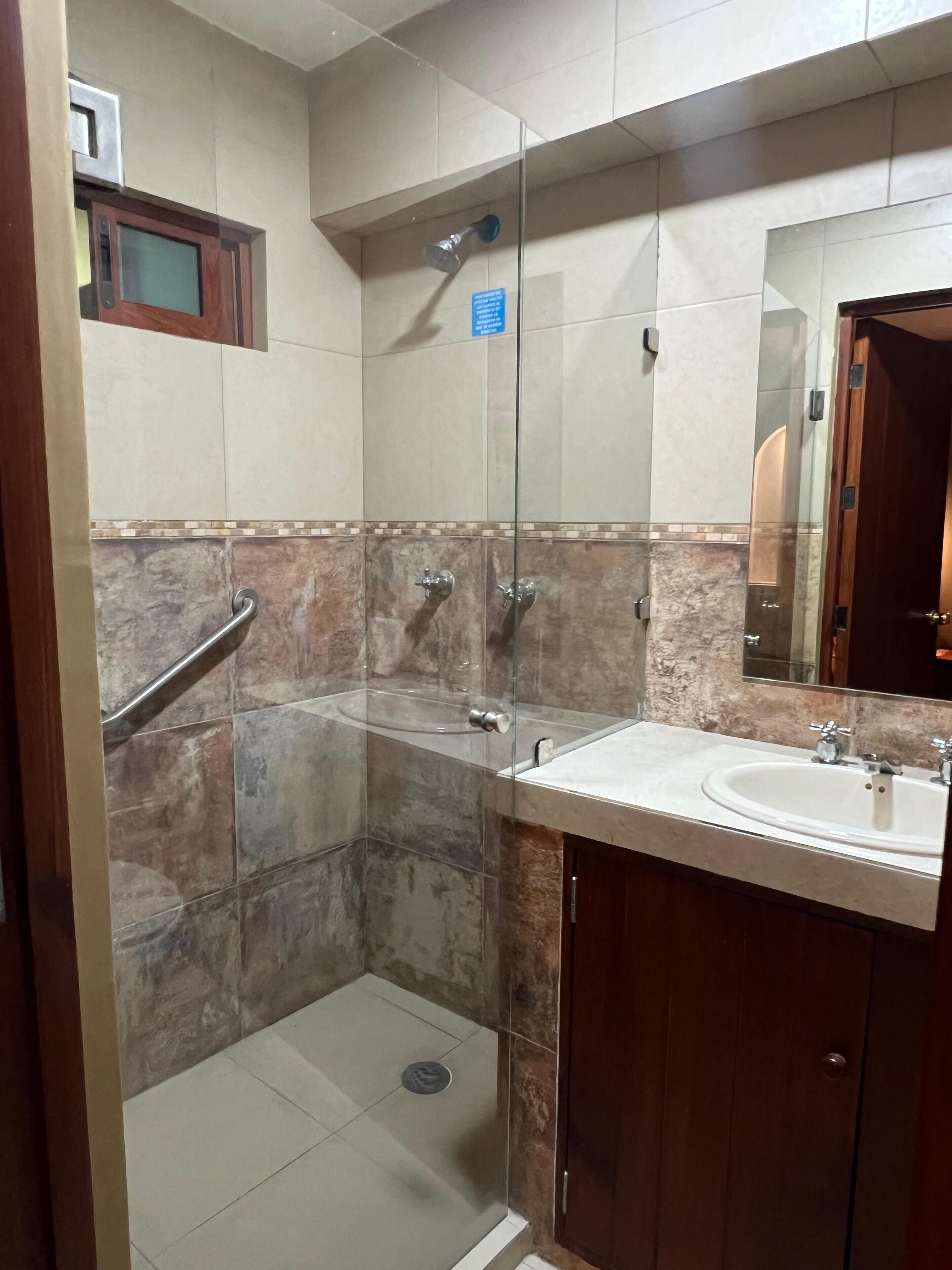 A modern bathroom with a glass shower enclosure, a sink, and a mirror.