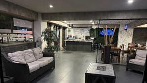 A modern lobby with a sofa, dining area, and a reception desk.