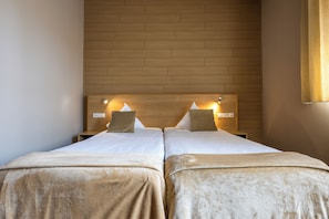 A double room with two beds, each with a headboard, a bedside table, and a lamp. - Hotel INGREDI (Bree)