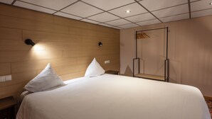 A hotel room with a large bed, two pillows, a wooden headboard, a wall-mounted light, and a wardrobe with a mirror. - Hotel INGREDI (Bree)