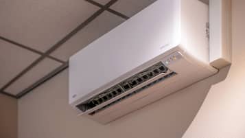 A white air conditioning unit mounted on a wall with a visible control panel and vents.