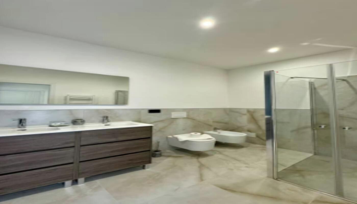 A modern bathroom with a glass shower enclosure, a vanity with a mirror, and a toilet.