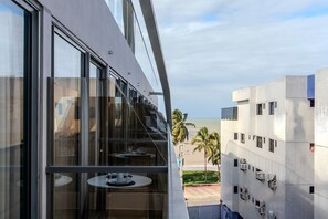A modern building with large windows, a balcony with tables, and a view of the beach. - Setai Yach (Joao Pessoa)