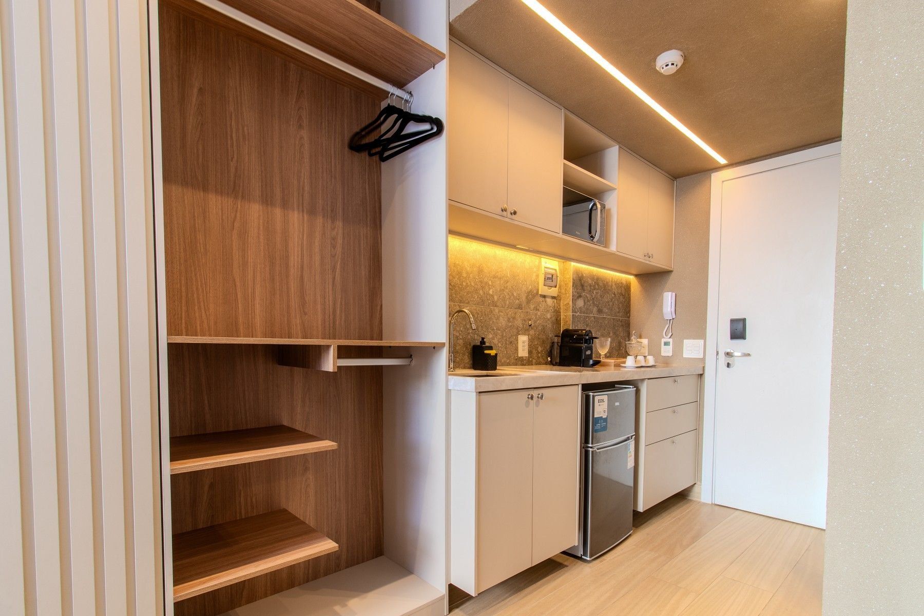 Una cocina moderna con electrodomésticos integrados, estantes de madera y una puerta blanca.