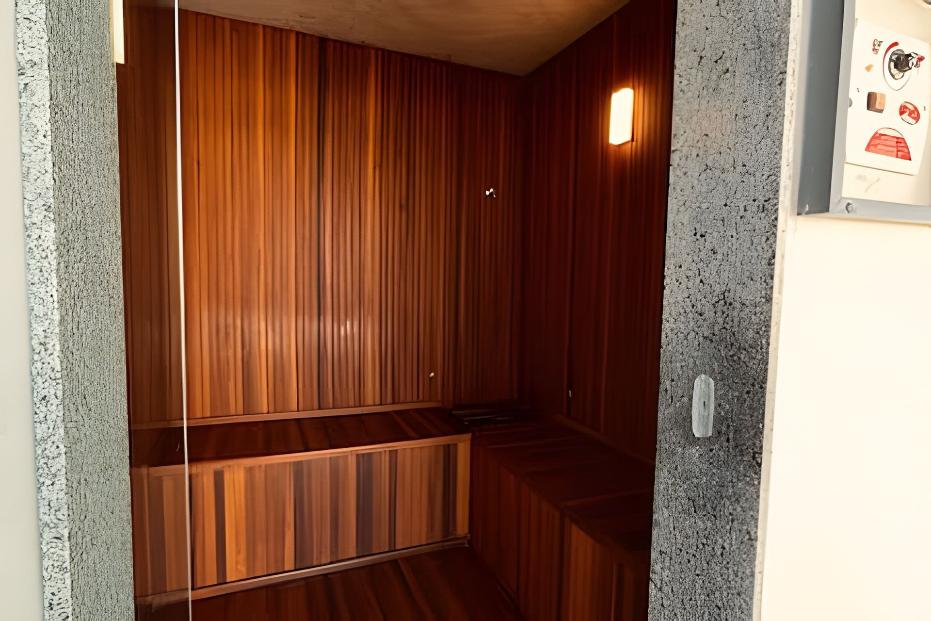 Une pièce avec des lambris en bois, un banc et un luminaire fixé au mur.