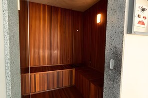 A room with wooden paneling, a bench, and a wall-mounted light fixture.