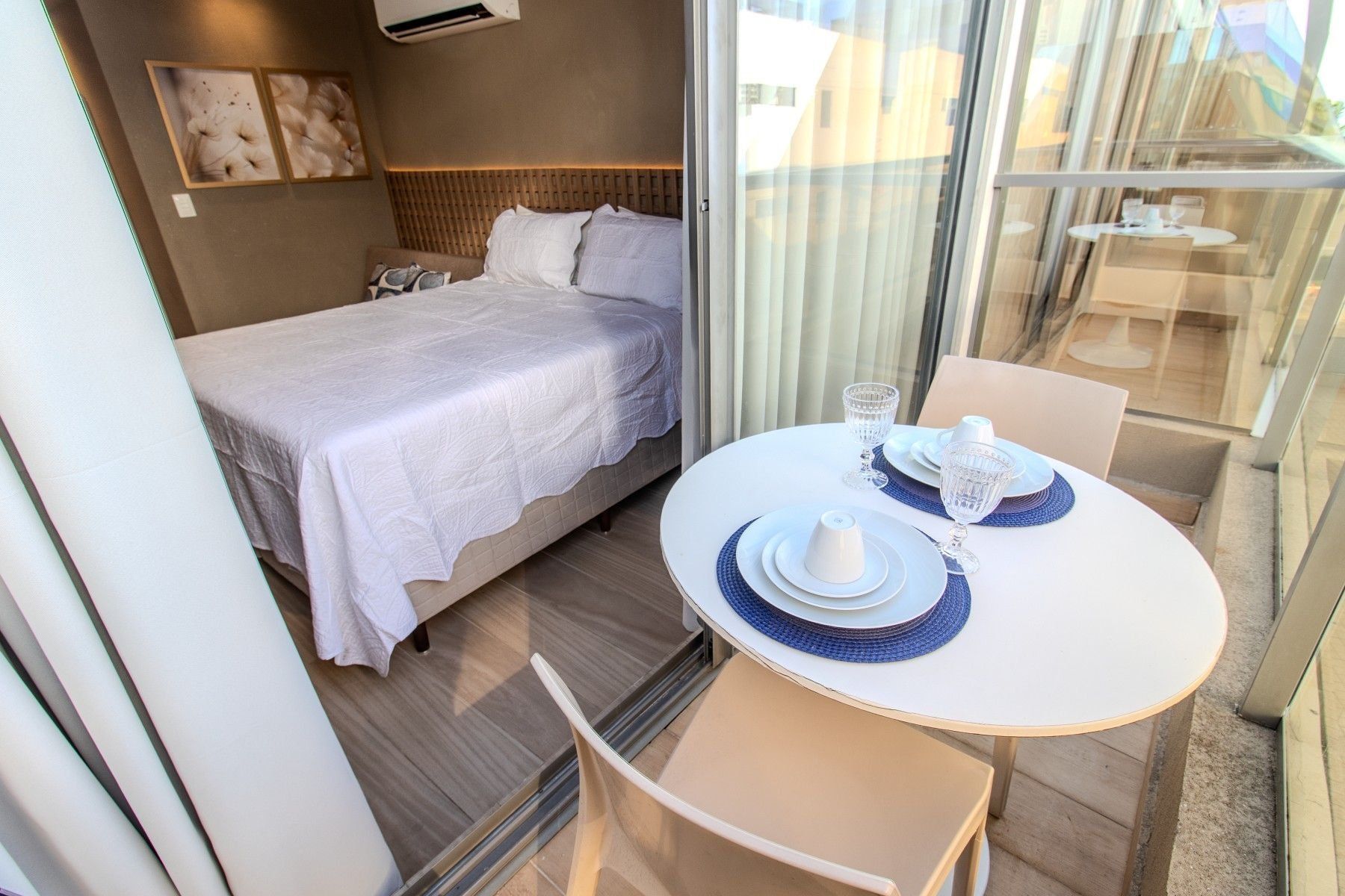 Habitación de hotel con cama, una mesa de comedor con sillas y vistas a través de un ventanal.