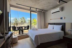 Ein Hotelzimmer mit Bett, Schreibtisch, Stuhl und einem Balkon mit Blick.