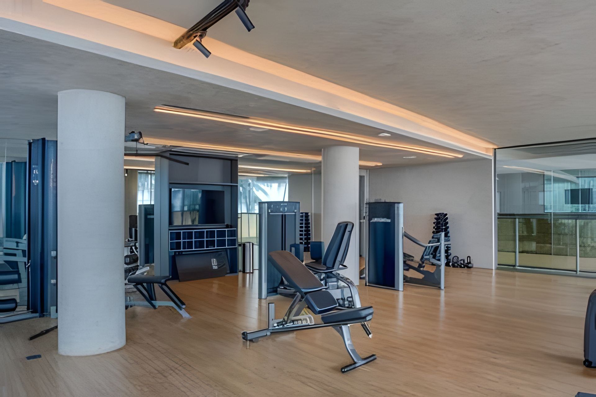 Un gimnasio moderno con equipo de ejercicio, ventanas amplias y un diseño limpio y minimalista.